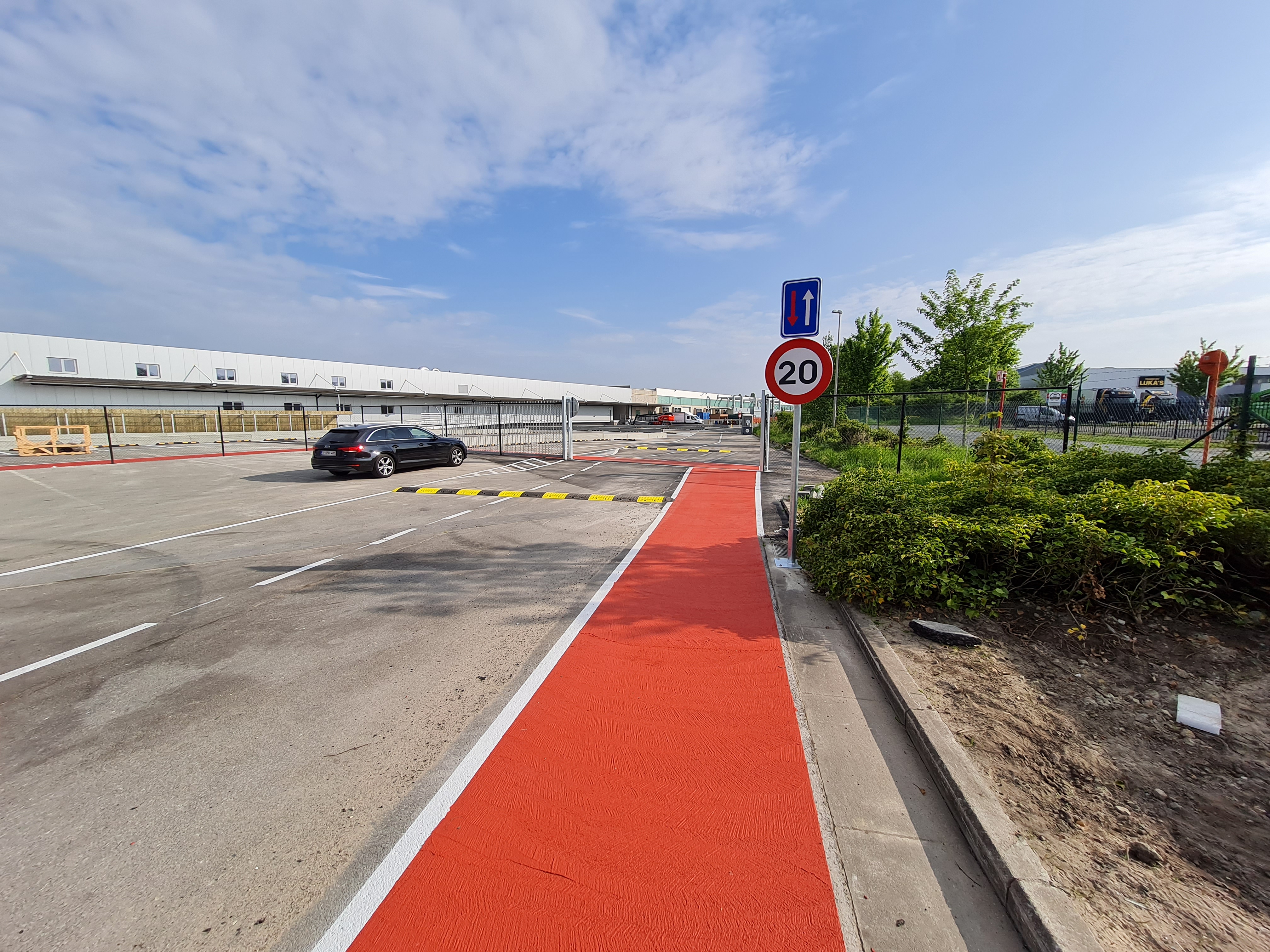 Professionele buitenparking met rode PMMA-belijning, parkeervakken en verkeersborden: project Evolut-ion
