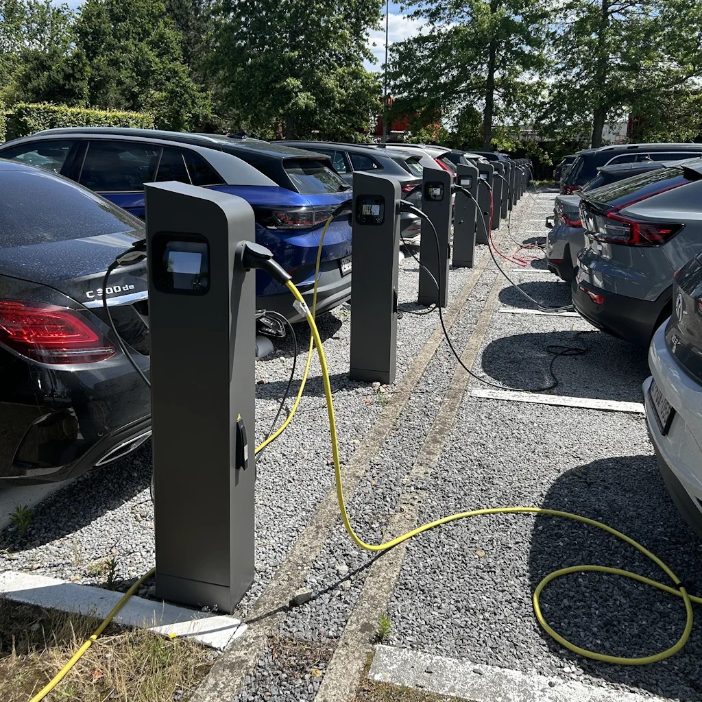 Rij laadpalen op een bedrijfsparking, meerdere elektrische bedrijfswagens aan het laden